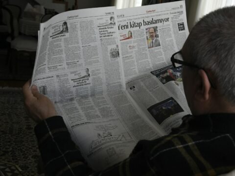 a man reading a newspaper while wearing glasses